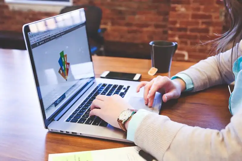 The image shows a woman using a laptop
