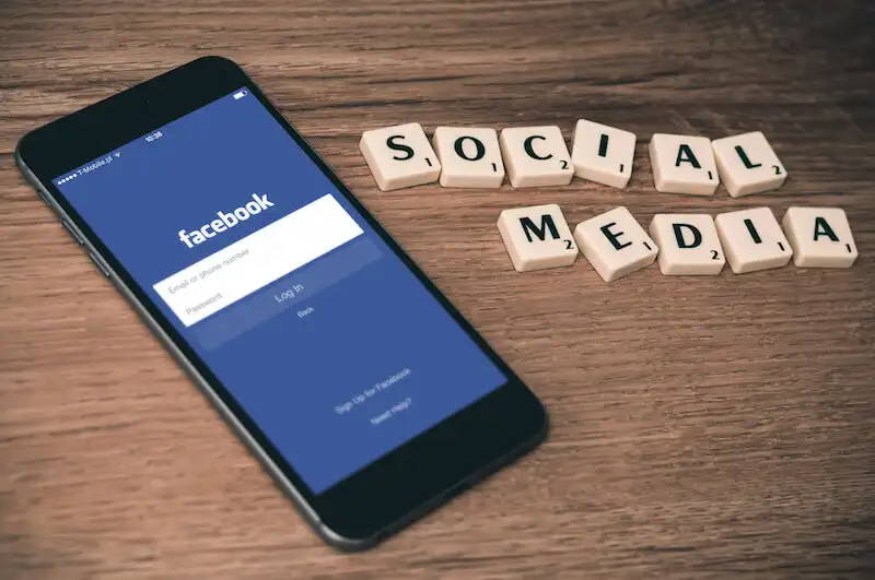 The image shows a smartphone, on its screen there is Facebook page. On the side of the smartphone it's written "Social Media".