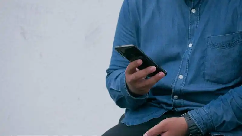 The image shows a man holing a smartphone. 