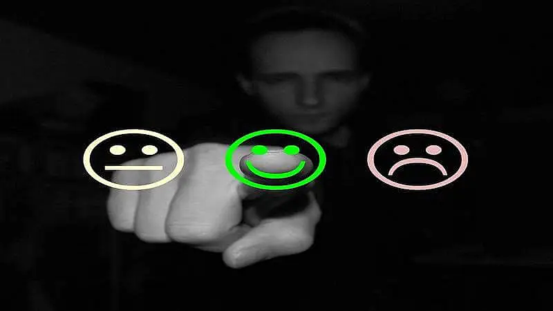 The image shows 3 emojis, and a person is pointing to emoji in the middle, which has a happy face.