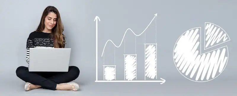 The image shows a woman using a laptop, sitting on the floor, and on her side there are the drawings of 2 charts.