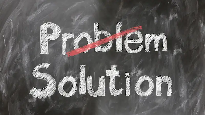 The image shows the words "Problem" and "Solution" written on a chalkboard, the word "Problem" is crossed. 