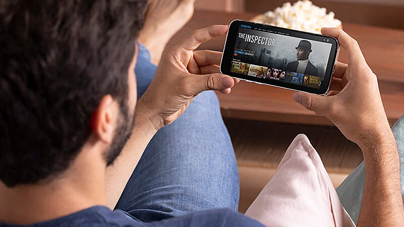 Foto de um homem sentado de frente para uma televisão