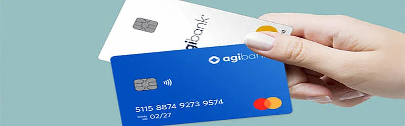 Foto de uma mão segurando dois cartões de crédito Agibank