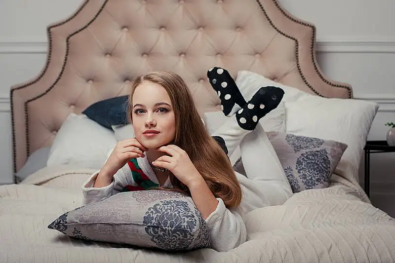 The image shows a girl laying in bed, she is wearing an onesie.