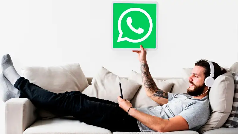 Foto de uma pessoa segurando um celular com o WhatsApp aberto