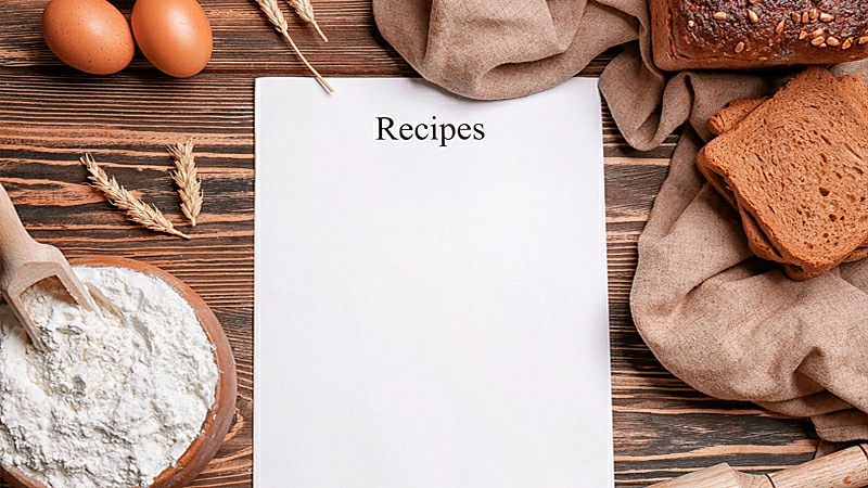 Foto de um livro de receitas e ingredientes em cima de uma mesa