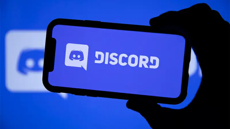 Bot de música Discord Foto de um computador aberto na tela do discord e um celular com o icone do Discord