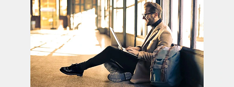 homem sorrindo ao usar seu notebook e ler uma carta de agradecimento ao cliente