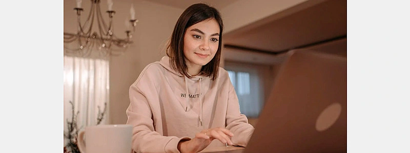 jovem sorrindo ao ler uma carta de agradecimento ao cliente em seu computador