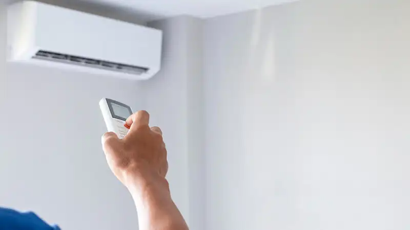 Cinema em Casa imagem de uma pessoa configurando o ar condicionado com um controle remoto