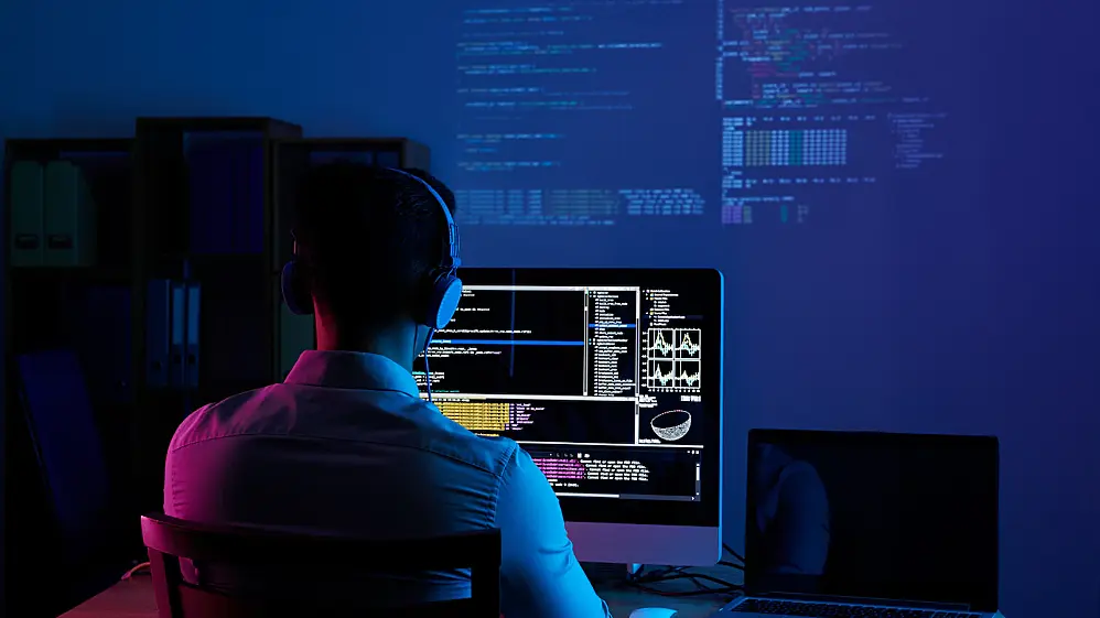 Foto de un hombre trabajando en el ordenador con códigos de programación