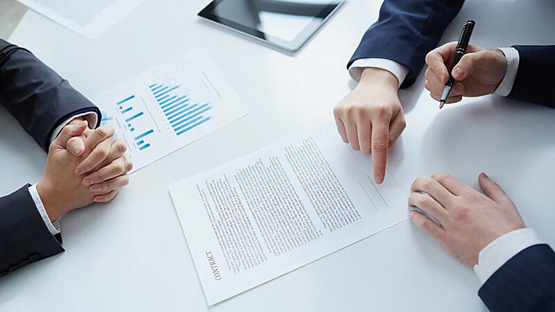 Foto de duas pessoas sentadas e vários papeis na mesa