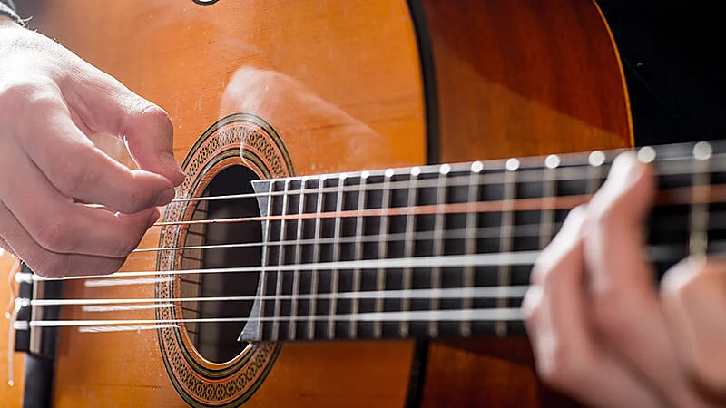 mulher praticando um acorde com pestana em um violão de nylon