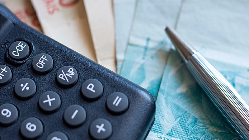 Foto de um homem segurando uma calculadora