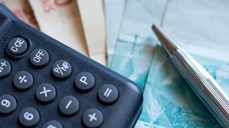 Foto de um homem segurando uma calculadora