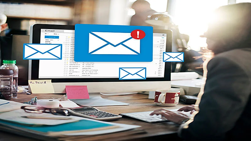 Foto de uma pessoa usando um computador e ícones de email na tela