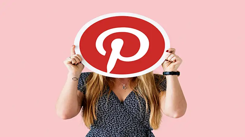 Foto de uma mulher segurando uma placa com a logo do Pinterest