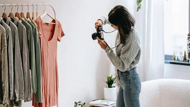 Foto de una mujer tomando fotos de ropa colgada en perchas