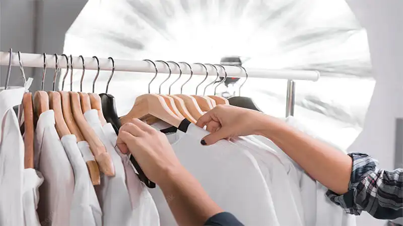 Foto de una persona eligiendo ropa en un perchero