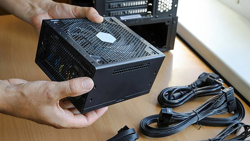 imagem que mostra uma pessoa segurando uma fonte de alimentação para PC com as duas mãos