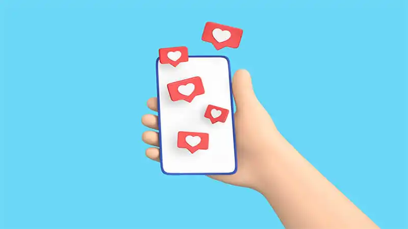 Imagem de uma mão segurando um celular com um ícone de curtida do Instagram