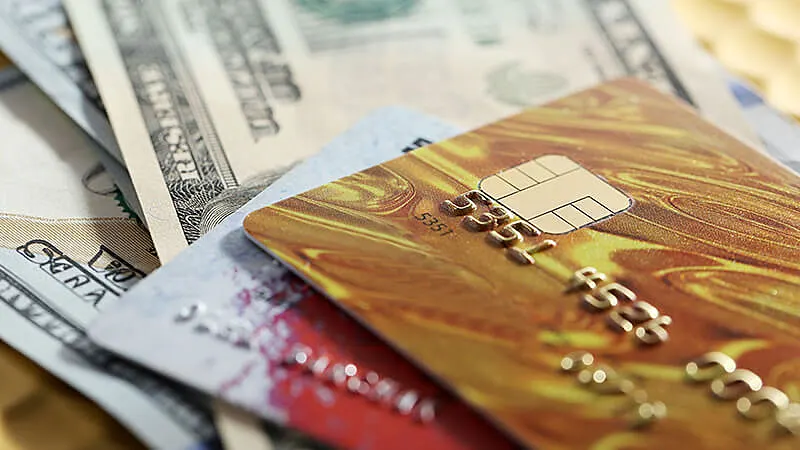 Foto de notas de dólares e dois cartões de crédito