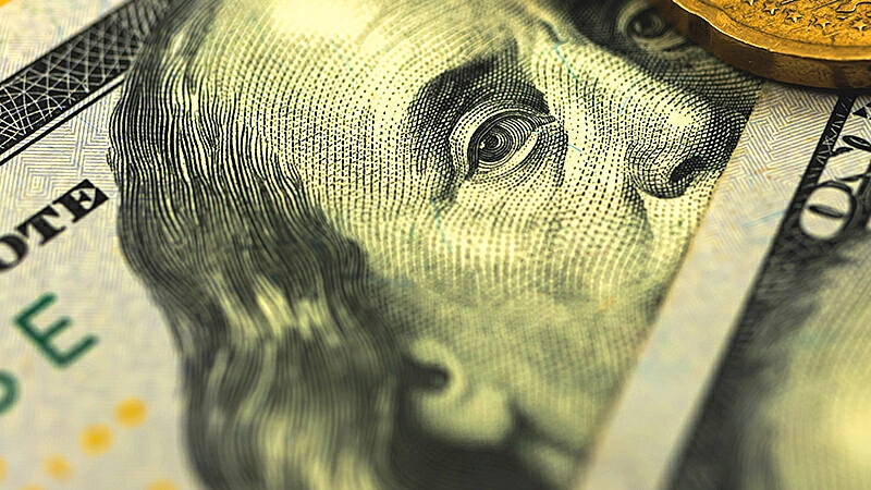 Foto de uma mão segurando várias notas de 100 dólares