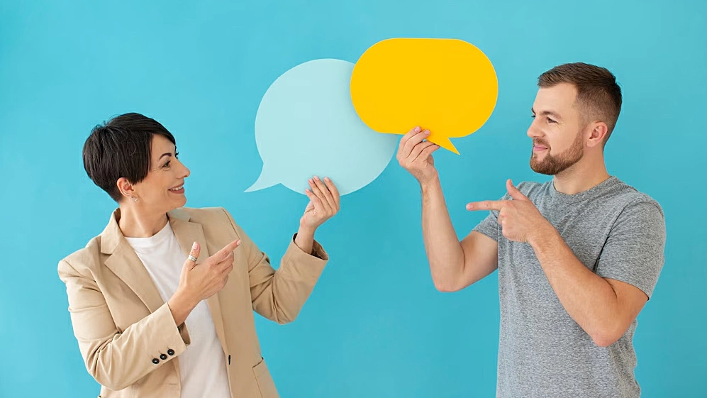 Foto de dos personas sosteniendo una burbuja de diálogo de papel recortada
