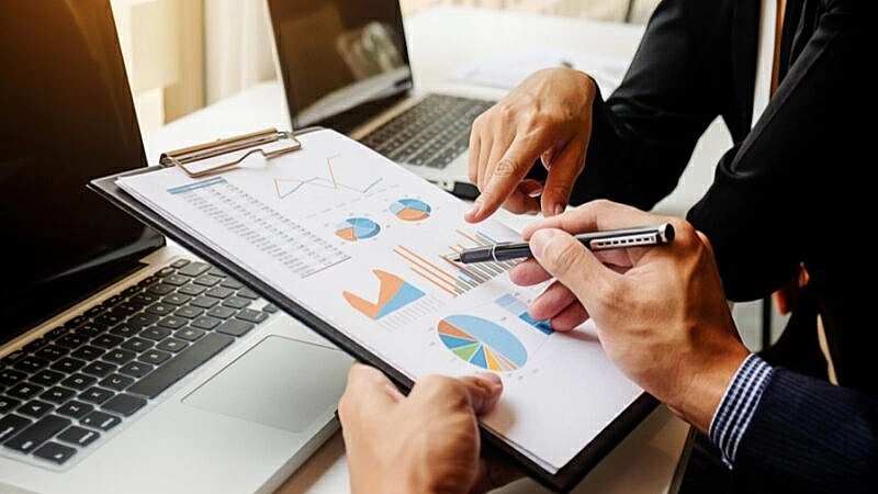 Foto de um homem segurando uma prancheta com diversos gráficos