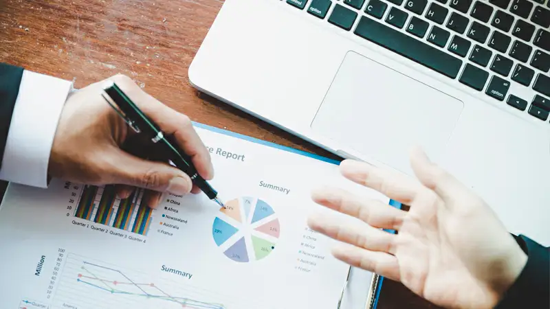 Contabilidade para ecommerce Foto de uma pessoa analisando gráficos em uma mesa