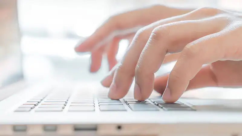 foto bem próxima de mãos digitando em um notebook