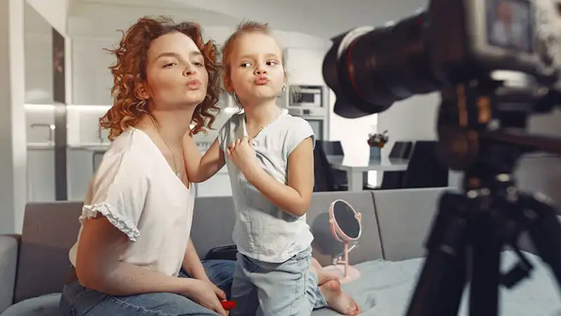 Fotografa mostrando uma foto em sua camera para uma bebê que está sorrindo