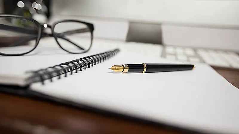 Uma caneta e um óculos em cima de um livro em inglês