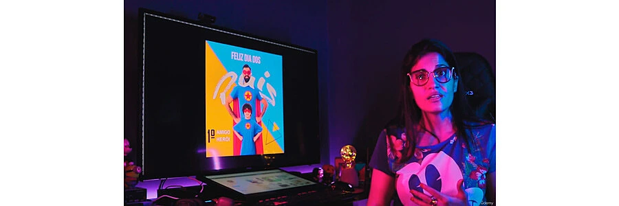 instrutora do curso de photoshop explicando sobre o conteúdo ao lado de sua estação de trabalho