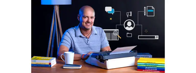 instrutor do curso de storytelling em uma mesa com uma máquina de escrever, caneca de café e vários livros