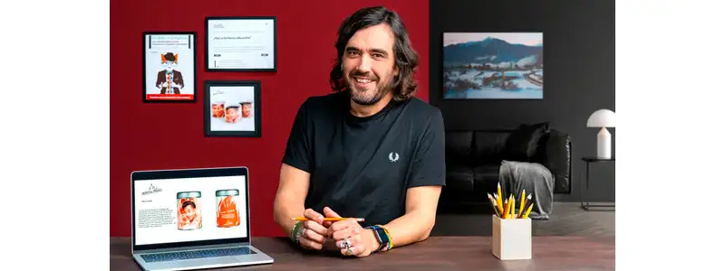 instrutor do curso de storytelling em uma mesa segurando um lápis, com um notebook e um porta treco repleto de lápis
