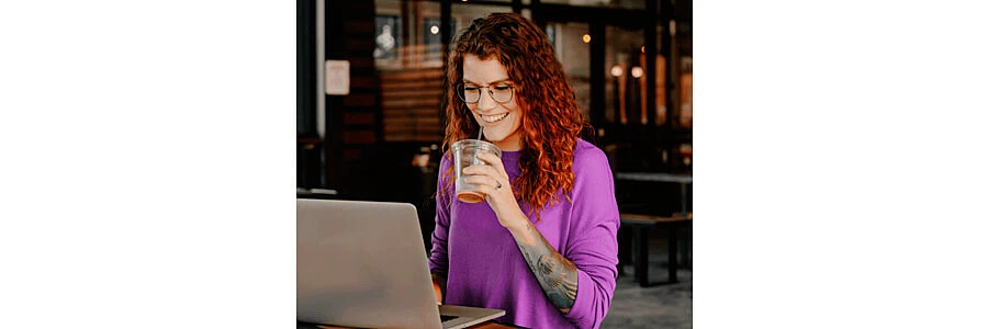 programadora full stack usando um macbook enquanto toma um copo de café