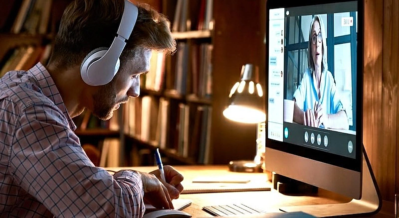 The image shows a man strudying in front of a computer while watching a video.
