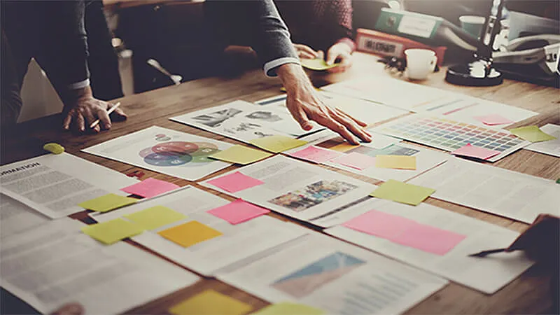 Foto de uma reunião e vários papeis em uma mesa