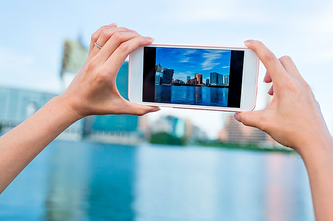 pessoa usando seu smartphone para tirar uma foto de uma praia