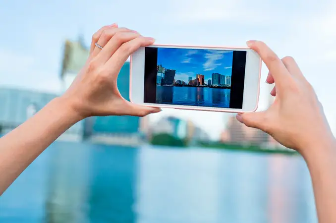 pessoa usando seu smartphone para tirar uma foto de uma praia
