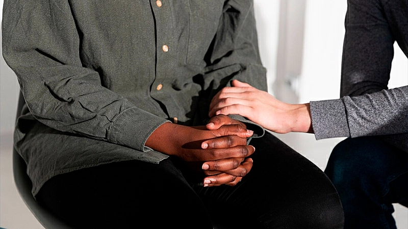 uma mulher consolando um homem que aparenta estar triste e cansado