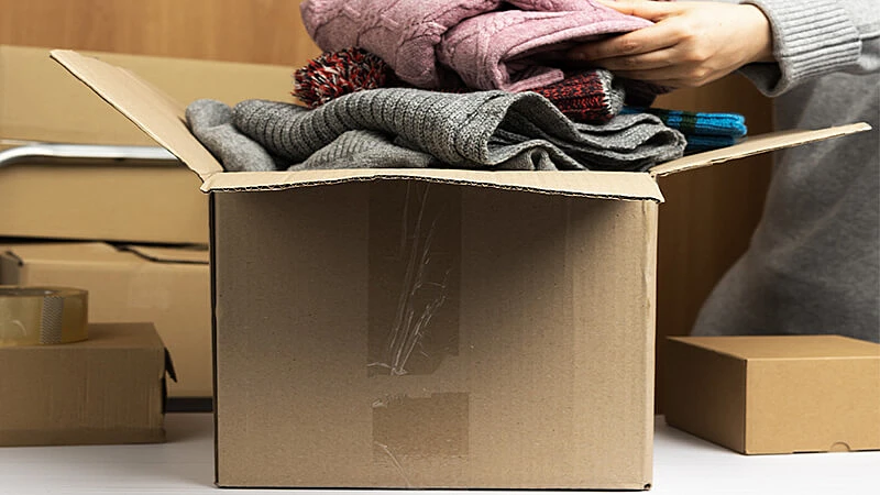 Uma pessoa colocando calças em uma caixa