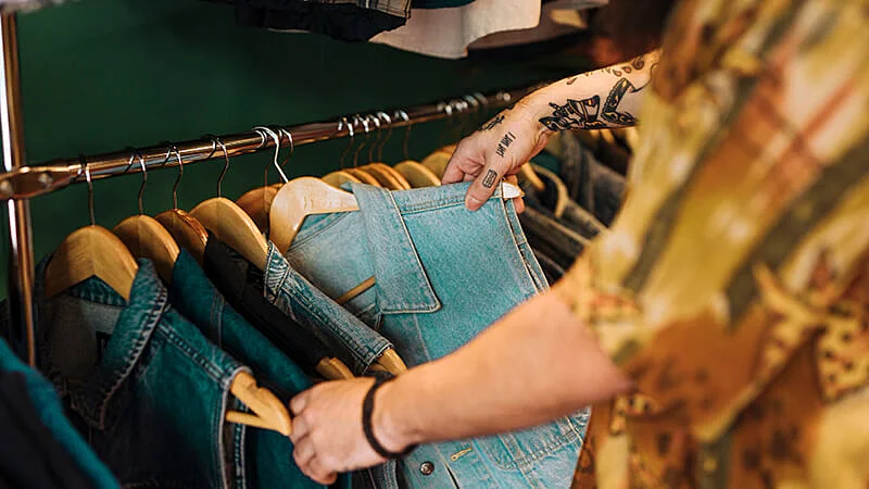 Uma mulher escolhendo roupas em uma arara