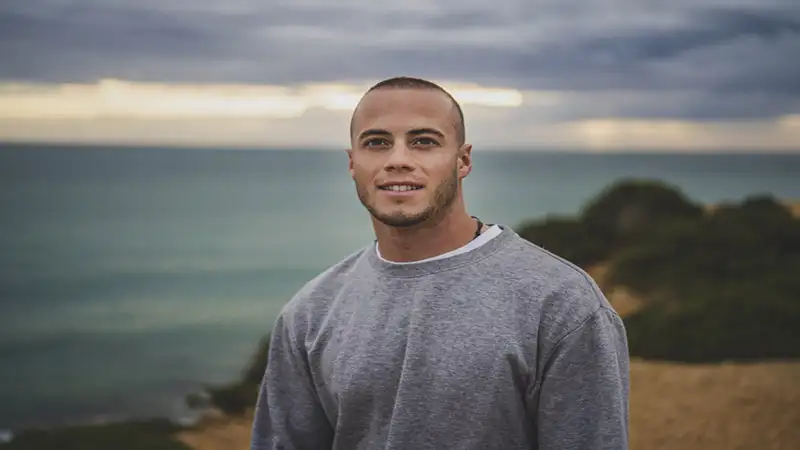 fotos para perfil do Instagram Foto de um homem com uma blusa cinza em uma paisagem com o mar ao fundo
