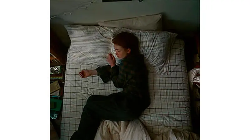 foto de uma mulher deitada na cama com feições tristes