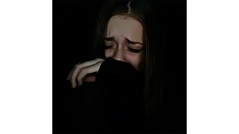 foto de uma menina chorando com a mão tapando a boca