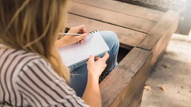 frases curtas Foto de uma mulher anotando em um bloco de notas