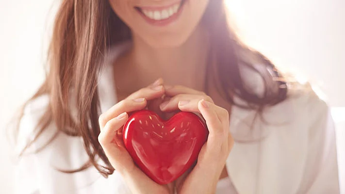 Foto de un corazón rojo en manos de una mujer